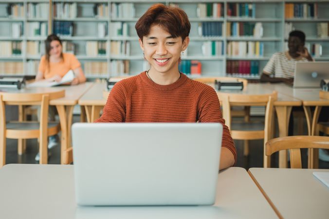 Asian student using laptop in library