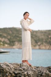 Gracious young woman standing on rocky cliff over sea with closed