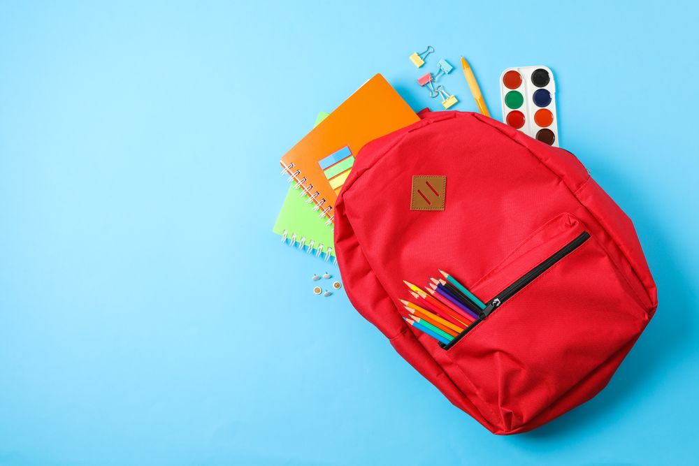 Flat lay composition with backpack and school supplies on color background