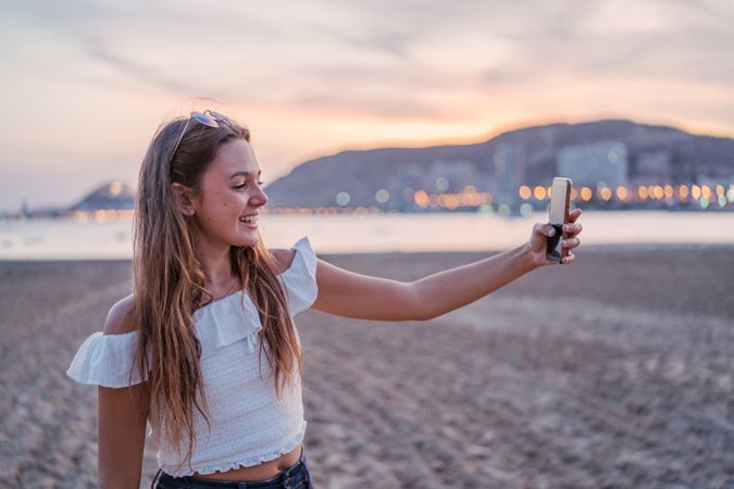Cheerful young woman using smartphone on resort