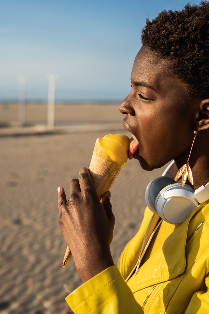 Cool female eating ice cream on beach