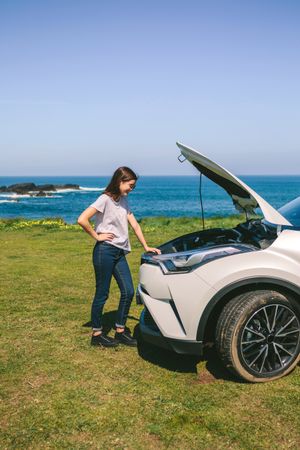 Woman looking engine of broken down car