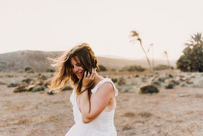 Woman in white dress in dry field in sunlight