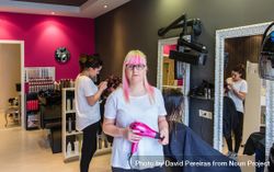 Woman with pink hair holding pink hairdryer in salon bx2YB5
