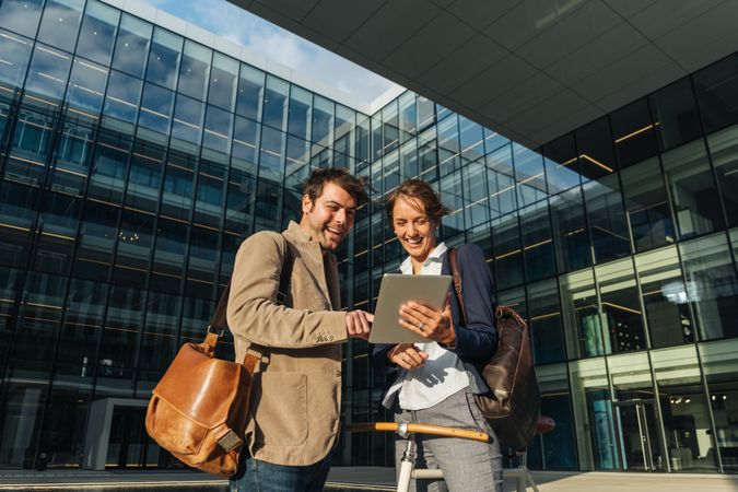 Cheerful colleagues using tablet after work