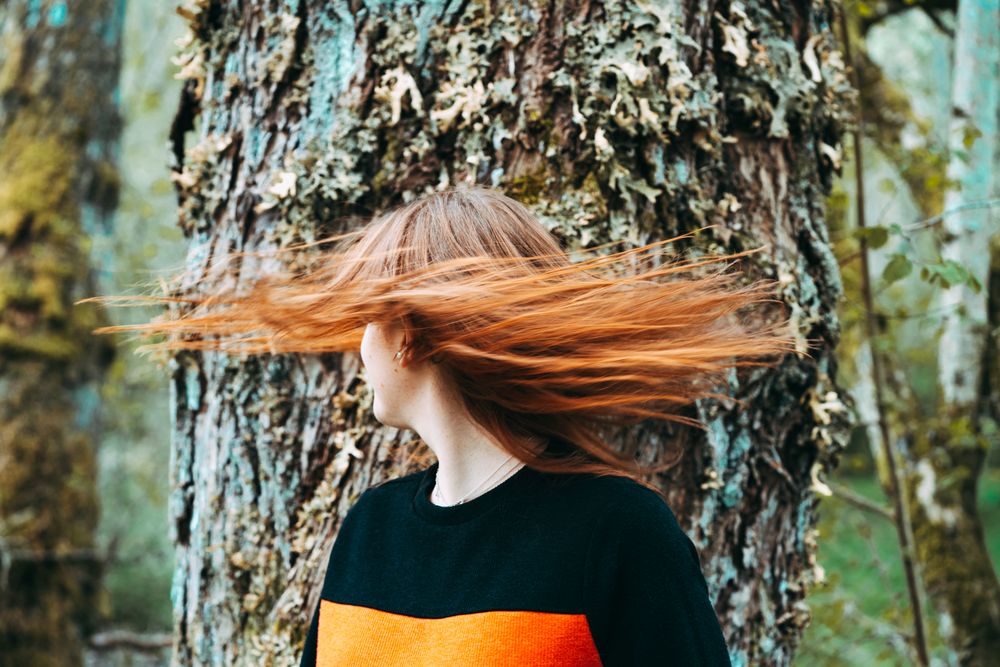 Casual redhead woman shaking with hair