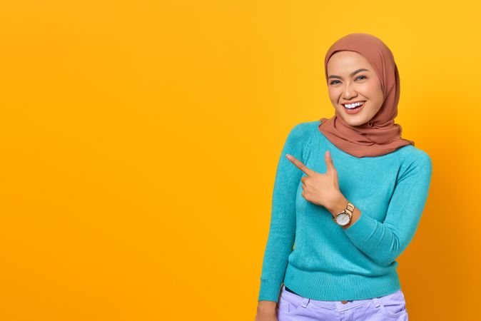 Excited Muslim woman posting to something diagonally above her