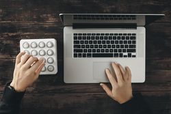 Top view of hands working on laptop and midi mixer control