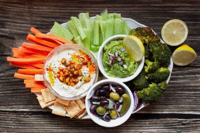 Tasty hummus and sauces decorated with bright cut vegetables on table
