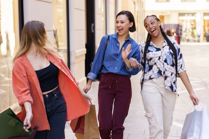 Women surprised to see each other on street with shopping bags