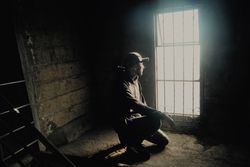 Young man sitting near window in abandoned building