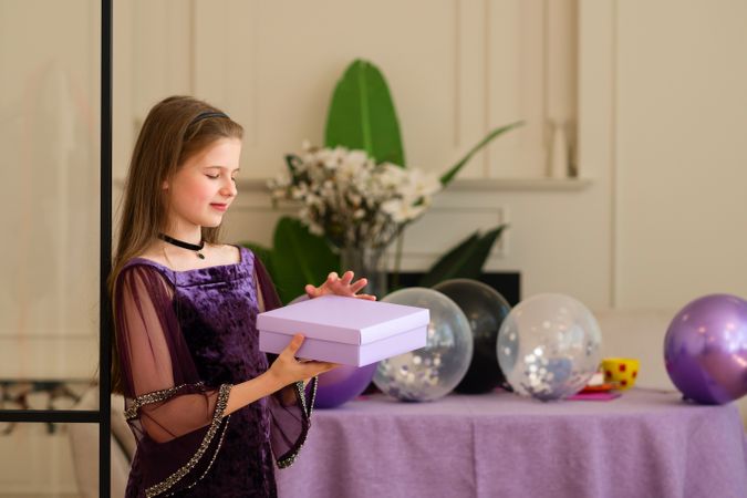 Girl in purple dress holding gift box at birthday party