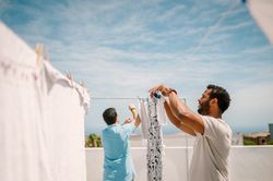 Multiracial men hanging clothes in bright day