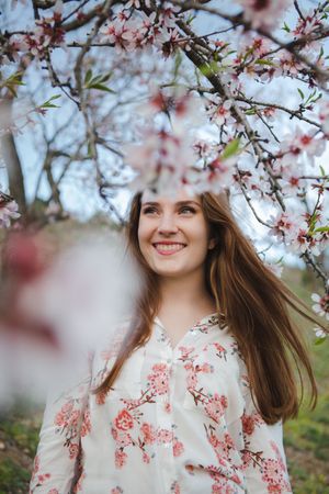 Young happy woman between trees in garden
