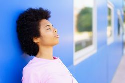 Calm woman leaning her head on blue building