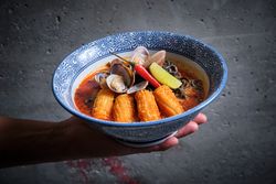 Typical hot ramen dish with fish broth in a bowl with noodles, squid, chilli, clams.
