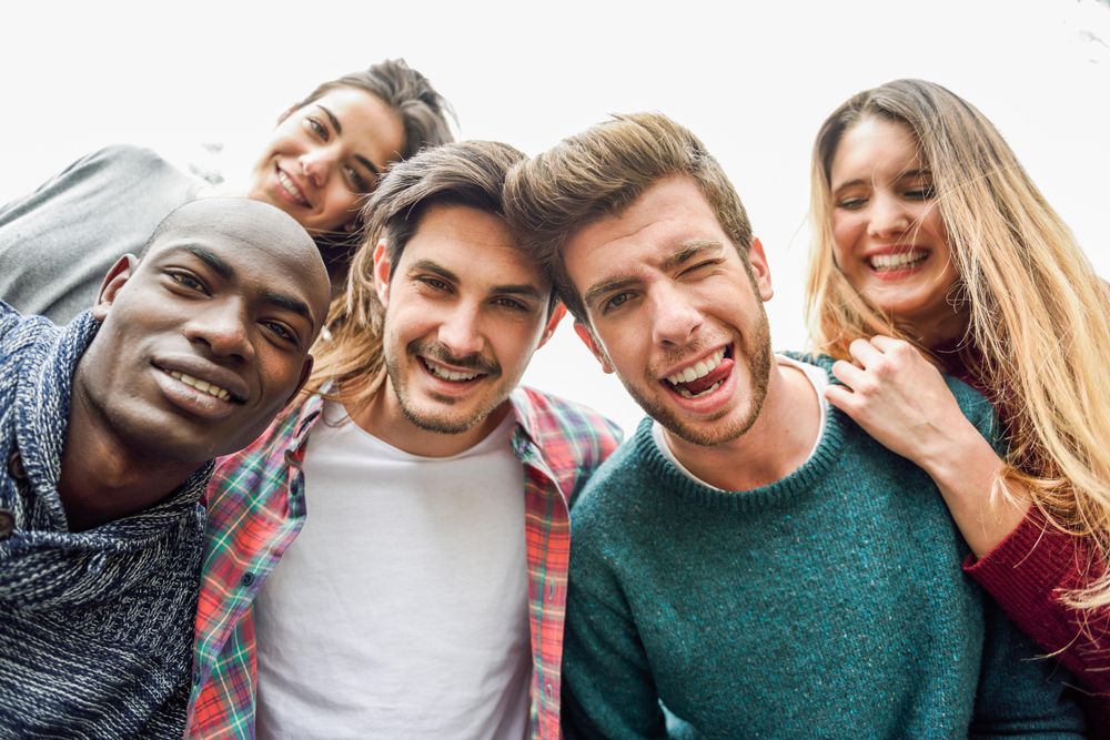 Group of smiling men and women looking down and smiling at camera