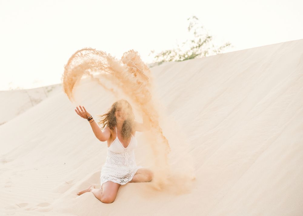 Woman having fun throwing sand in desert