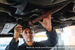 Mechanic working under a lifted car in repair shop 56V3j5