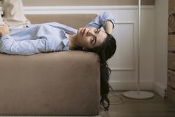 Wide view of young woman lying on a couch with her hair hanging down the side