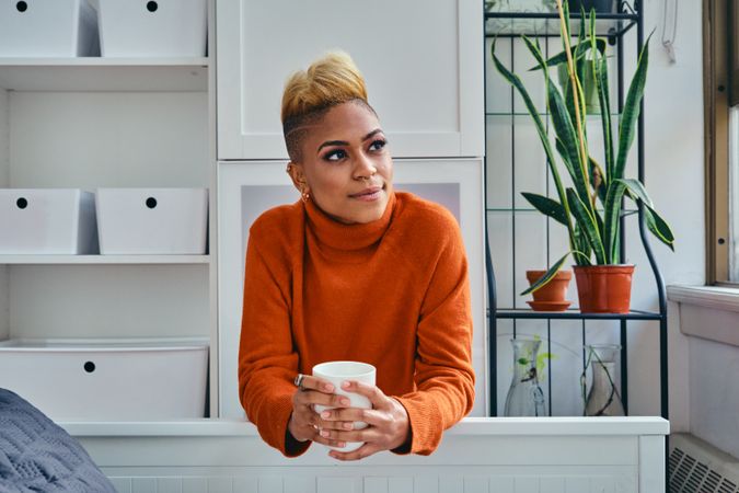 Thoughtful Black woman with a cup of coffee in a bright modern home
