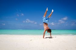 Unrecognizable male standing upside down near turquoise sea