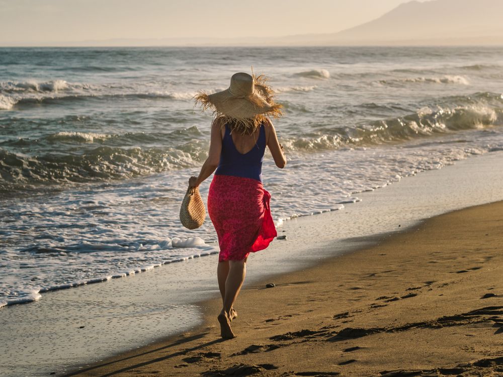 Woman in hat and running along seaside