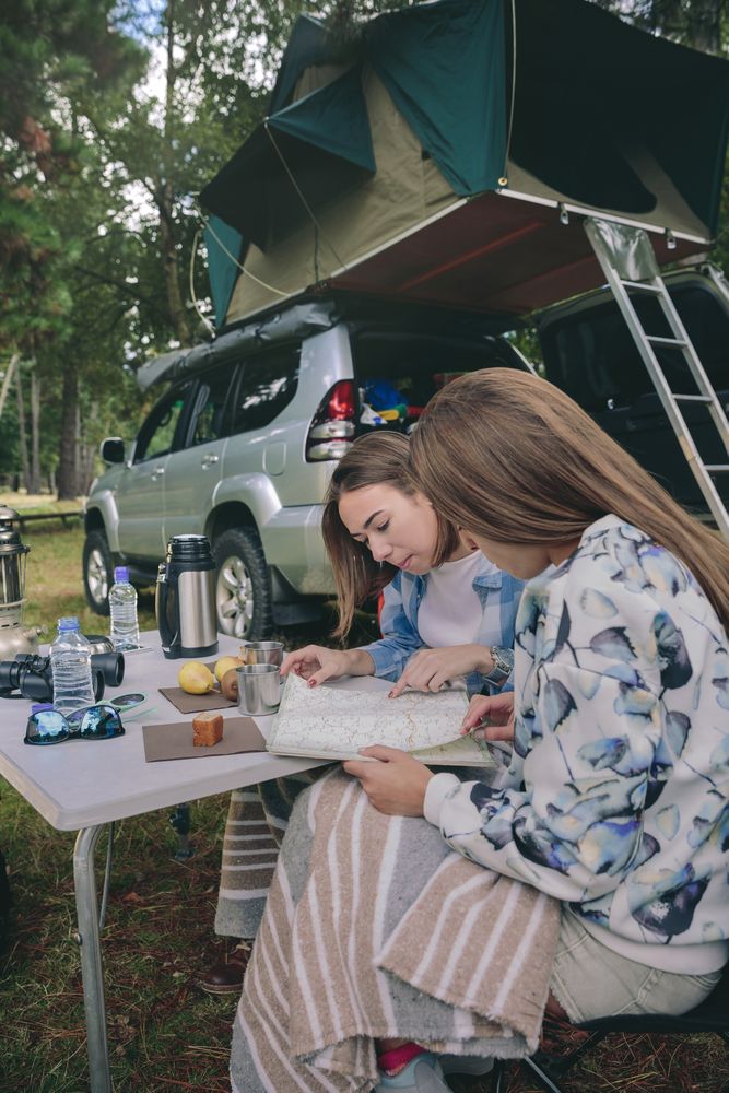 Young women looking road map with vehicle on background