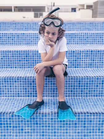 Disappointed preteen boy in diving mask and flippers on poolside