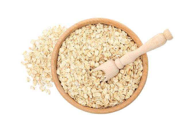 Bowl and scoop with oatmeal flakes isolated on plain background