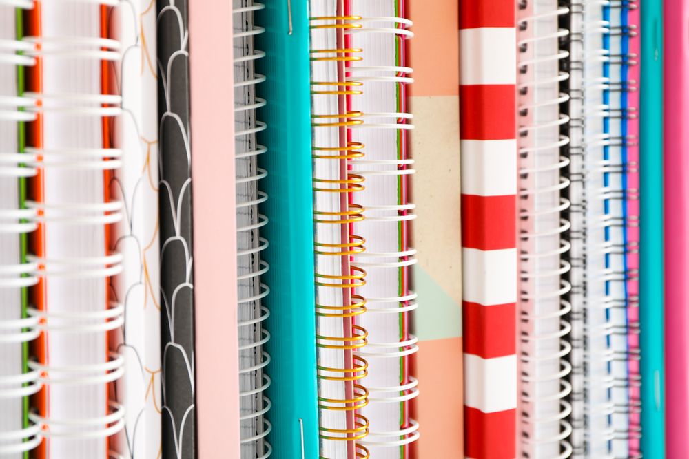 Stack of colorful books and copybooks as background, closeup