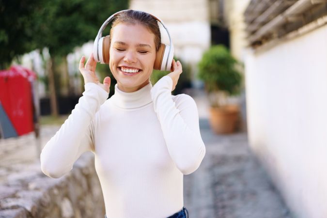 A Joyful Young Woman is Enjoying Her Favorite Music Outdoors While Wearing Headphones