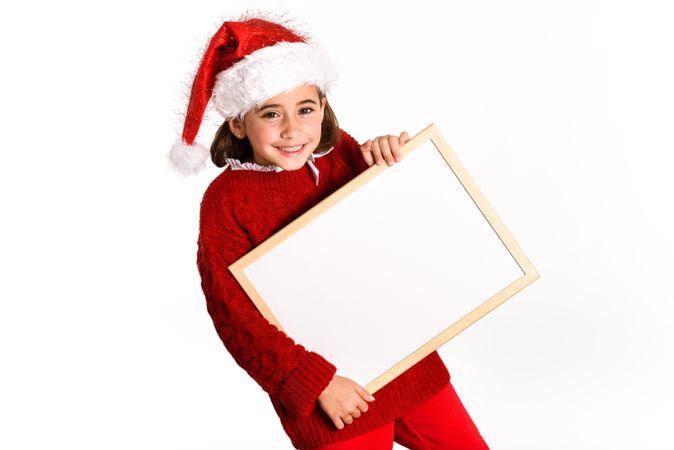 Child in Santa hat holding blank board