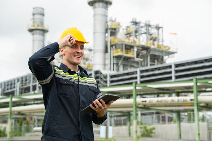Refinery oil engineer worker in protection hardhat with digital tablet inspecting at petrochemical factory.