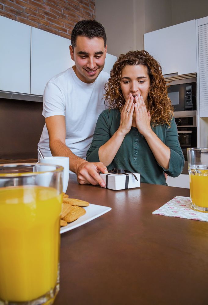 Man giving woman giftbox over breakfast