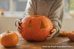 Person holding carved pumpkin 4OZxE5