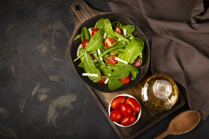 Arugula salad with tomatoes on dark background.