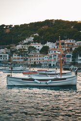 Sailboat on sea water against houses  on rocky shore