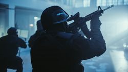 Portrait of Masked Armed SWAT Police Officer Storming Dark Seized Office Building with Desks and Computers.