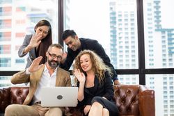 Group of colleagues in video call around leather sofa