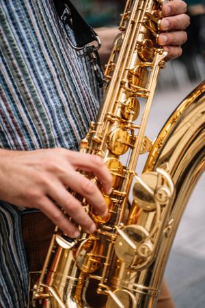 Crop view of male saxophonist playing sax in the street