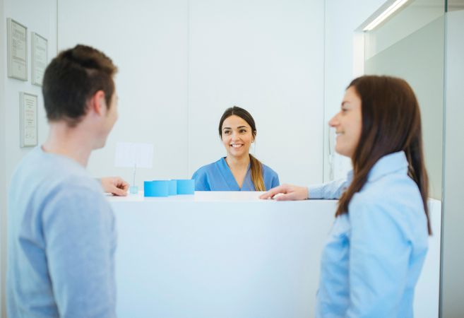 Cheerful administrator greeting clients on reception of dental c