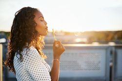 Woman with curly hair blowing bubbles outside