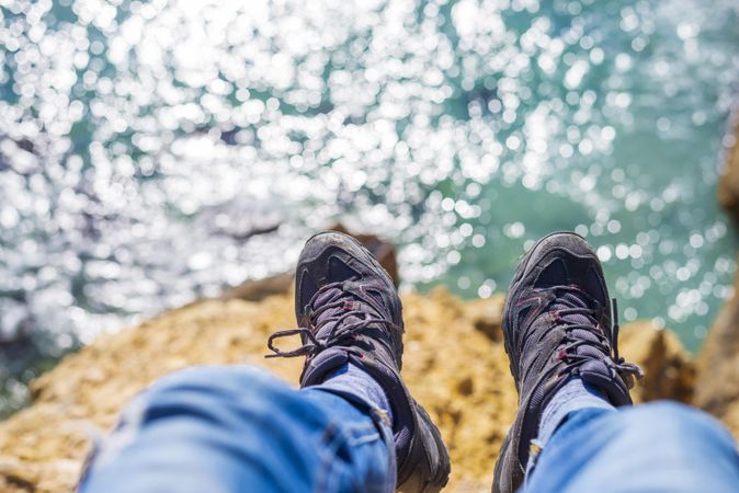 Looking down at boots on cliff with ocean below