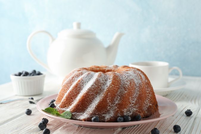 Cake with powder sugar and blueberry on wooden background, space for text