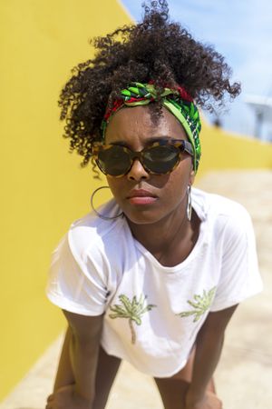 Serious Black woman with sunglasses and headband leaning towards camera
