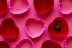 Pink and Red Heart-Shaped Cupcake Molds with Heart Chocolate on a Pink Background.