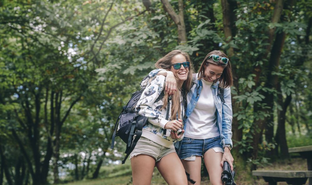 Women friends laughing while walking in forest