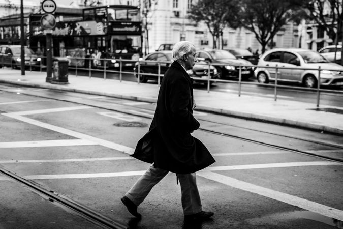 Side view of older man walking on pedestrian lane in grayscale