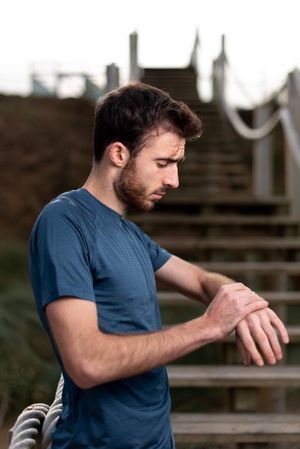 Sportsman in active wear looking at wrist watch on stairs